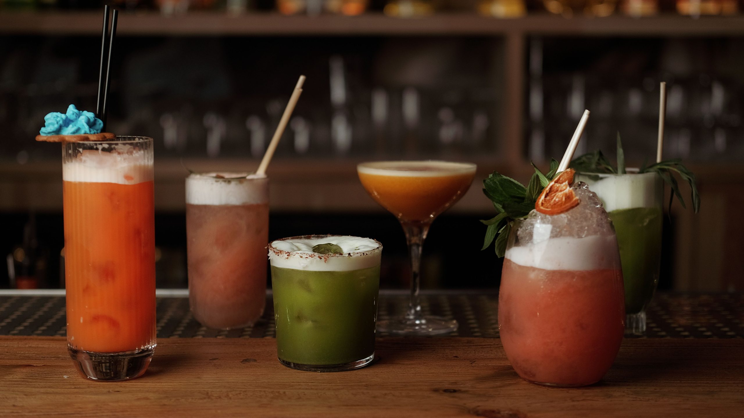 A row of six finished beverages lined up along a bar counter